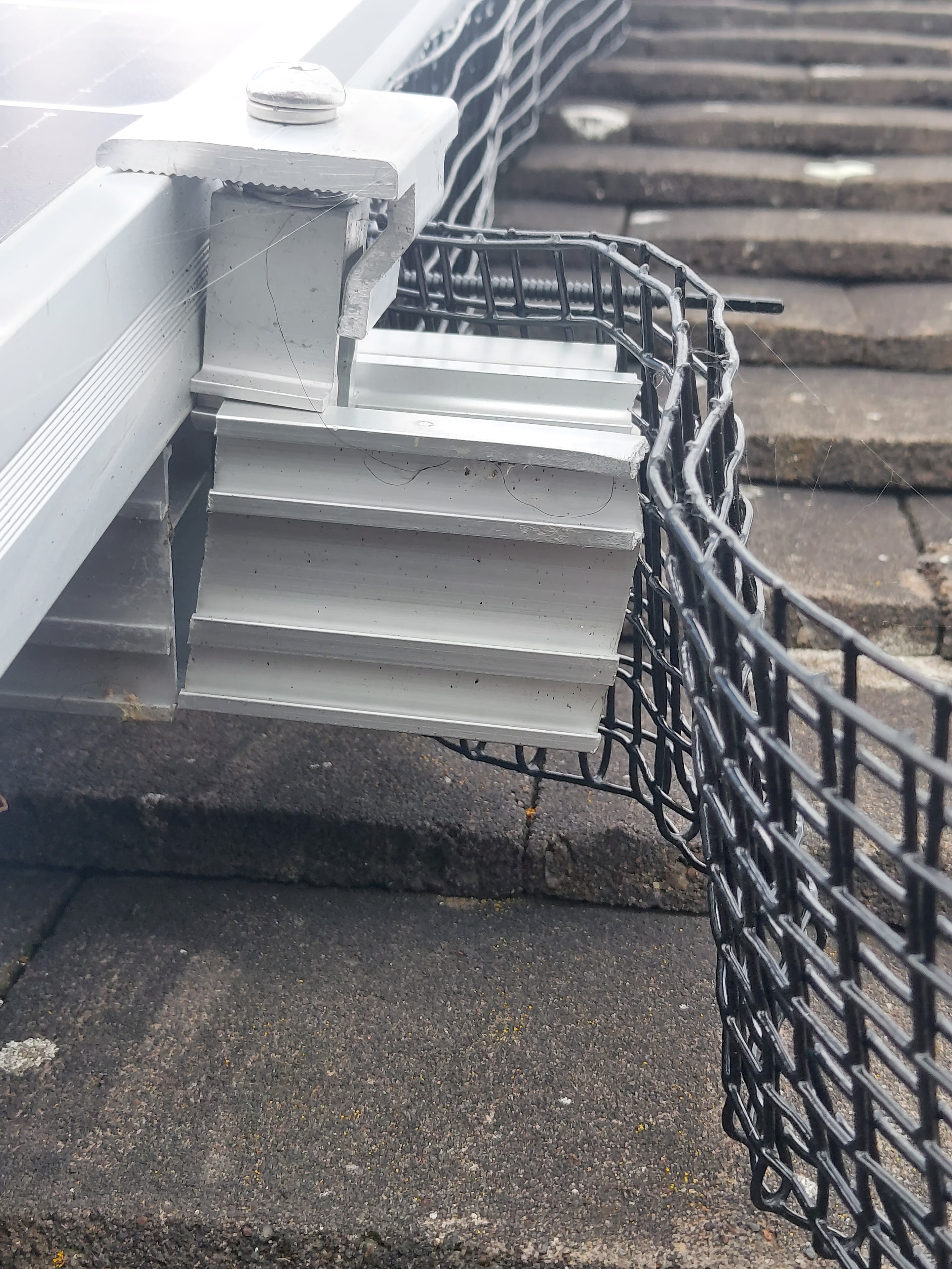 Bird-proofing mesh and mounting bracket close-up on roof edge